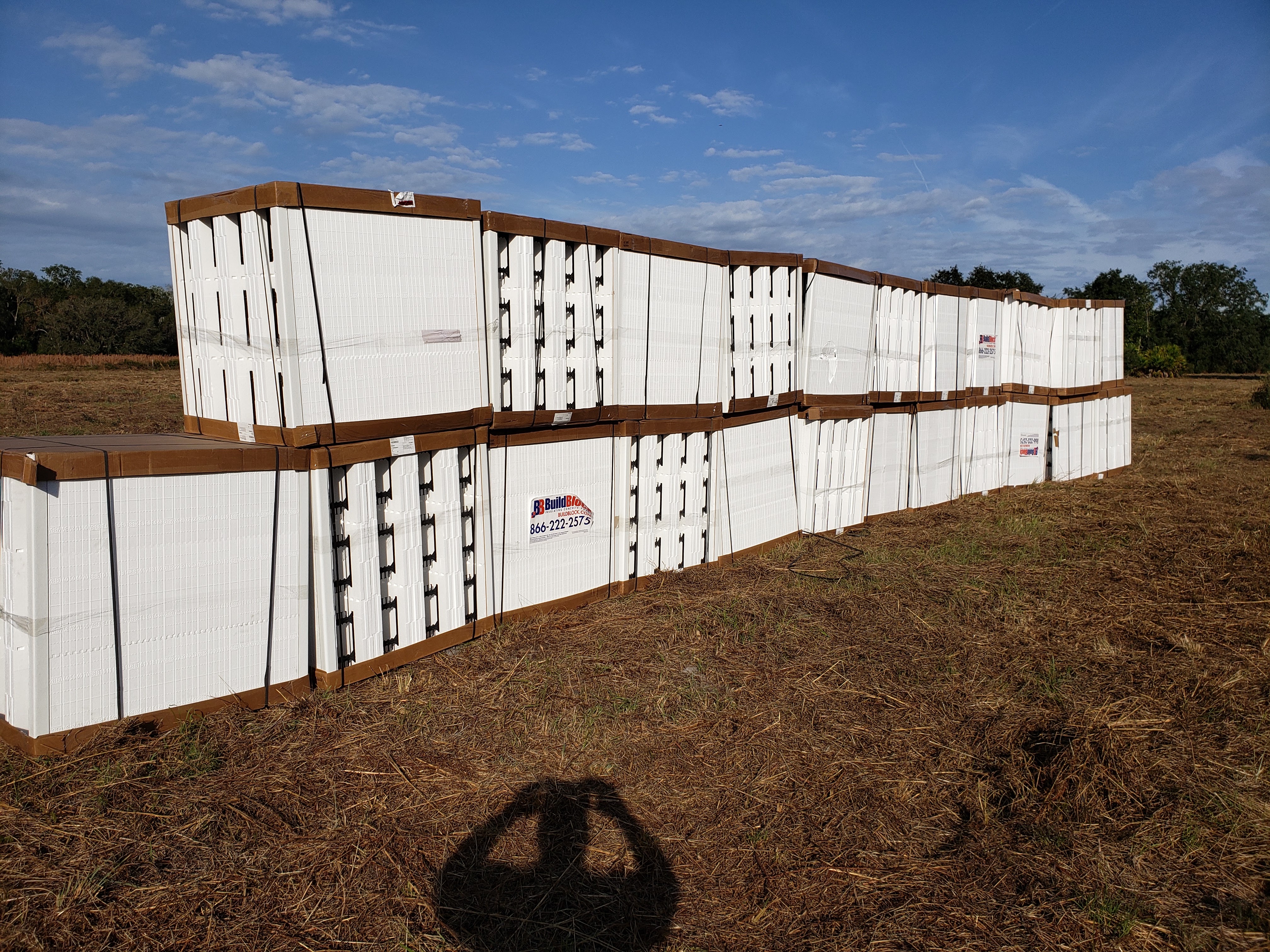A large stack of white ICF (Insulated Concrete Forms) blocks are neatly arranged and shrink-wrapped  