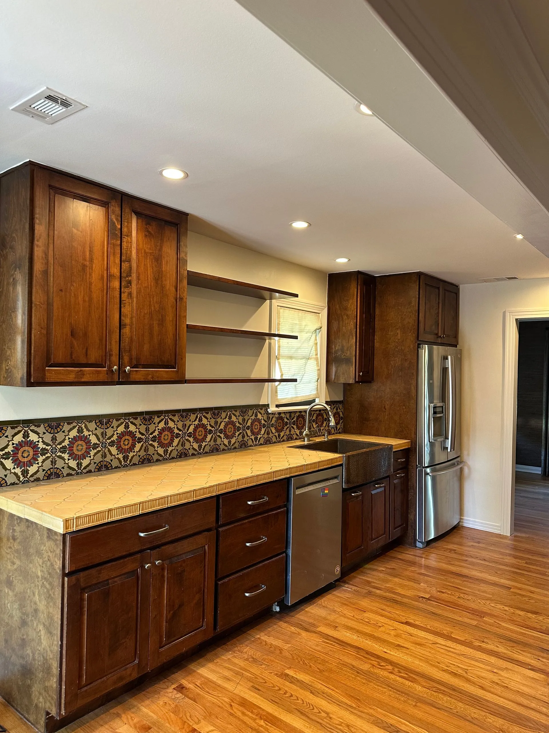 Beautiful remodeled kitchen featuring rich wood cabinetry, decorative tile backsplash, farmhouse sin 