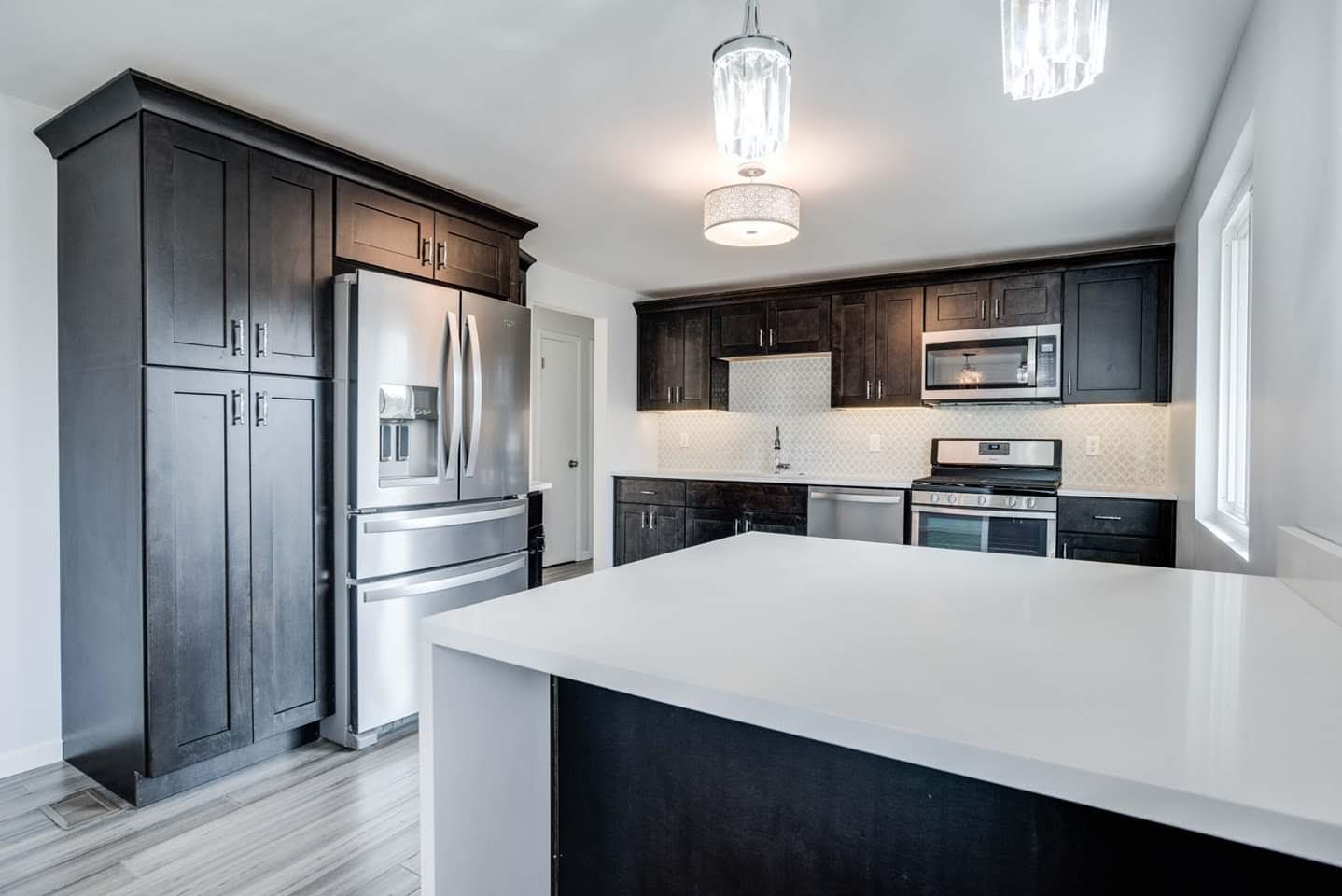 Kitchen remodeled with plywood cabinets that have soft closing hardware, quartz countertops, vinyl plank flooring, and stainless steel appliances.