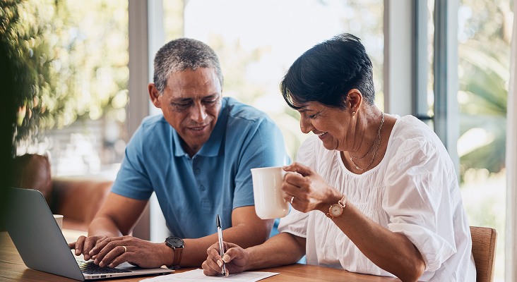 A couple filling out paperwork at their dining table.
