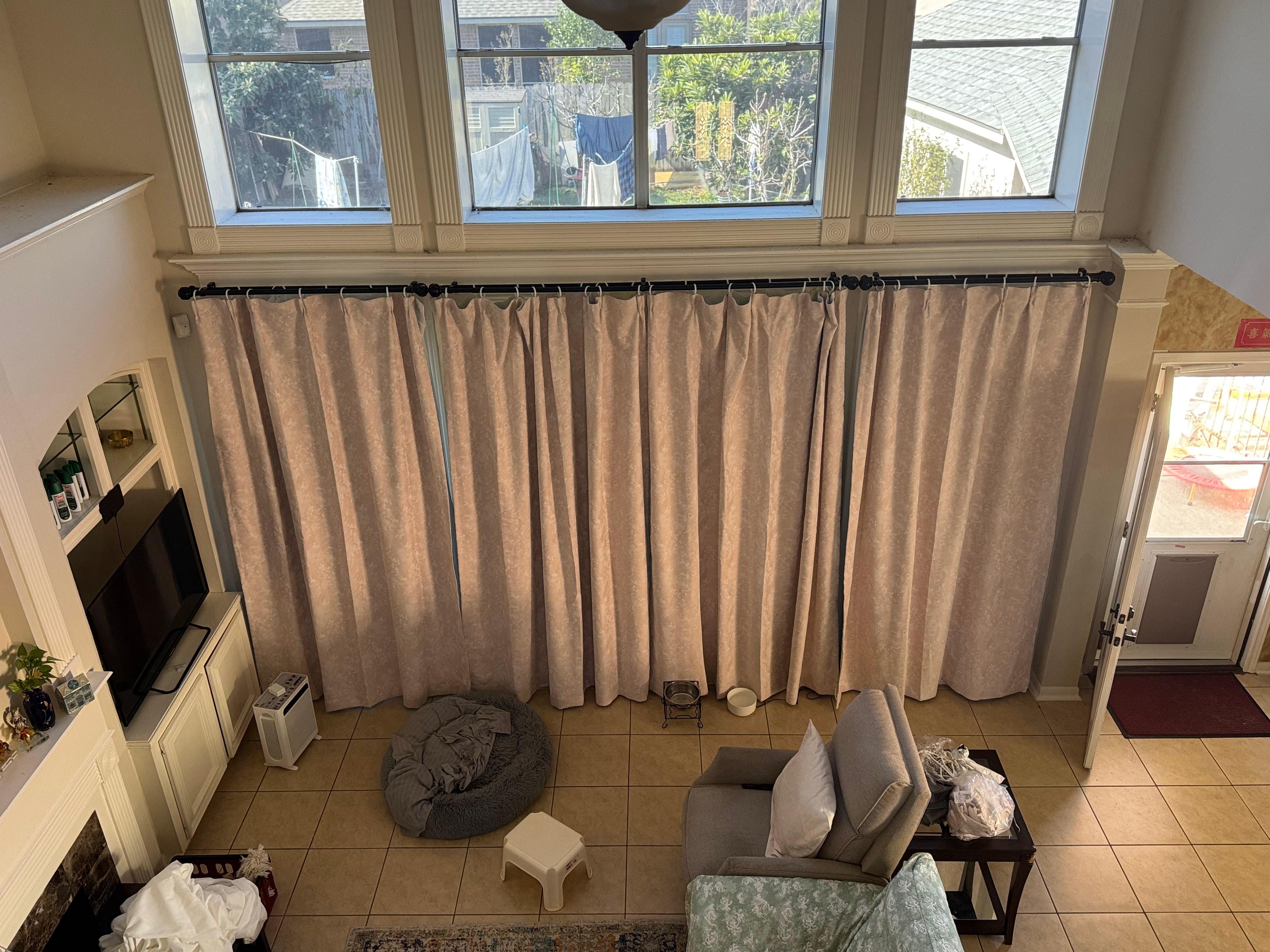 Floor-length curtains installed on tall windows in a two-story living room.