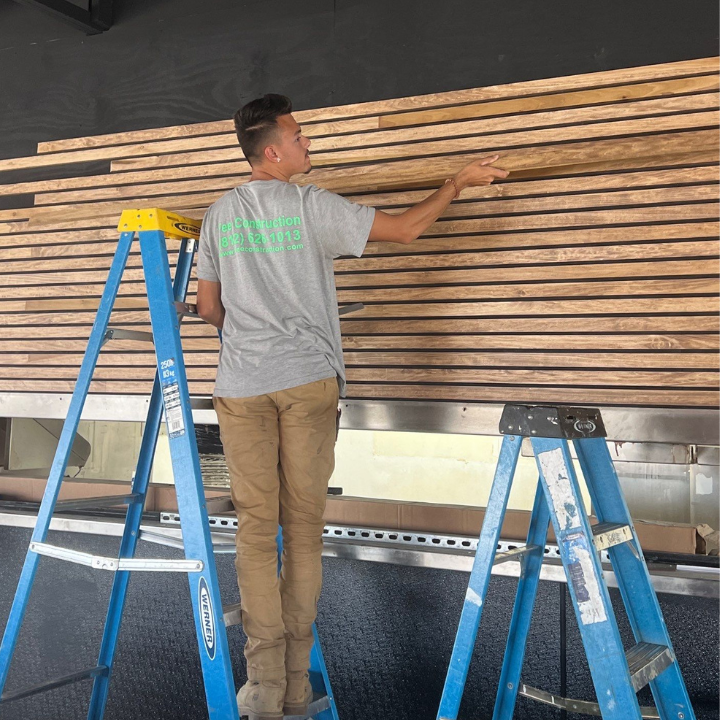 A Fee Construction LLC crew member installing a custom wood slat accent wall in Evansville, IN. Fee Construction's experienced team handles commercial and residential interior builds with precision and professionalism. From custom features to full renovations, no job is too big. Call (812) 626-1013 or visit feeconstruction.com for a quote.