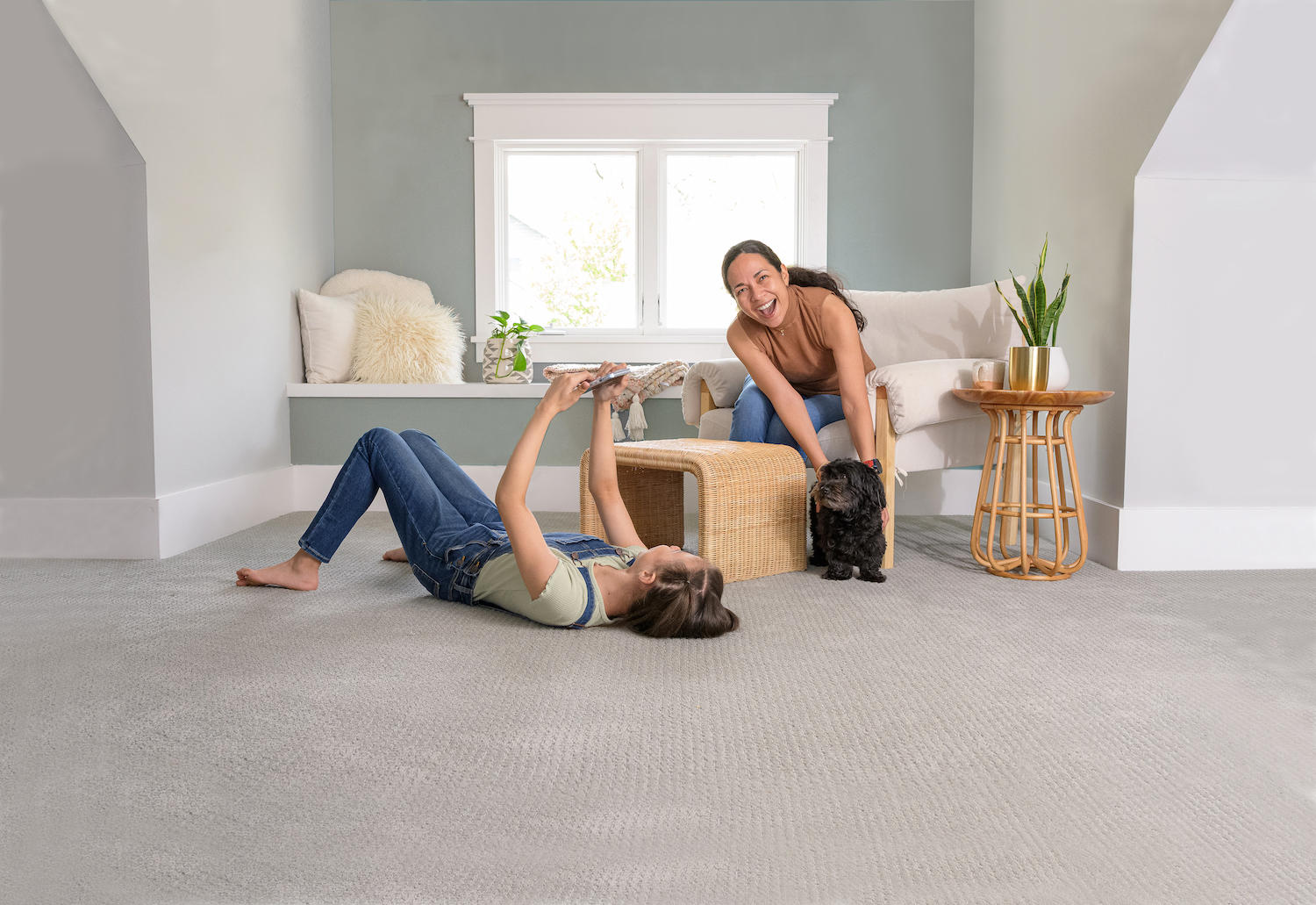 mother and daughter playing with dog next to upholstered furniture