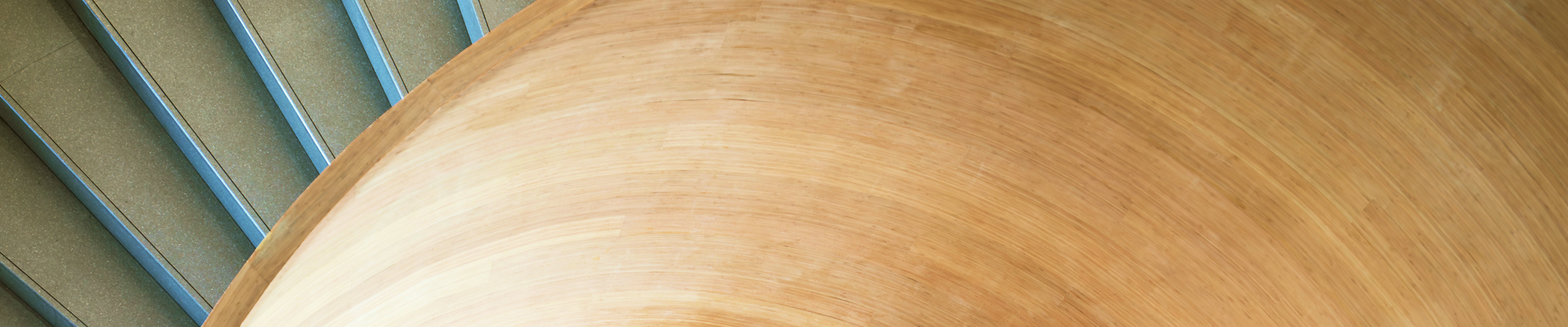 Close-up of an architecturally curved, modern wooden staircase.