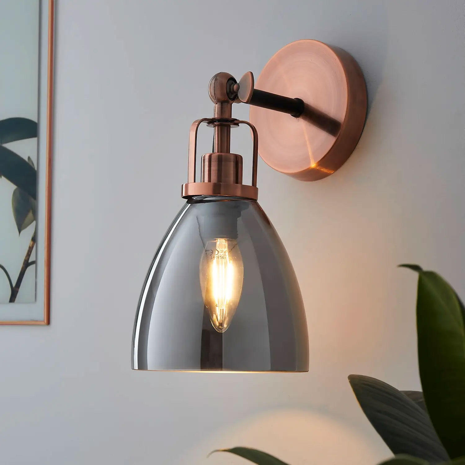 A rose gold and grey glass wall light