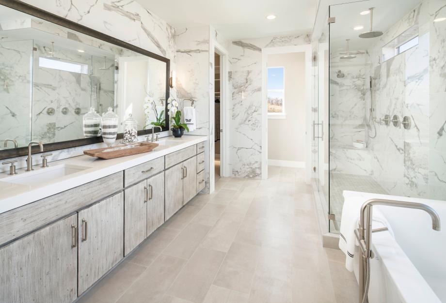 Lavish primary bathrooms with large walk-in showers and ample countertop space