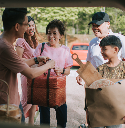 A multigenerational family unloading groceries from their car.