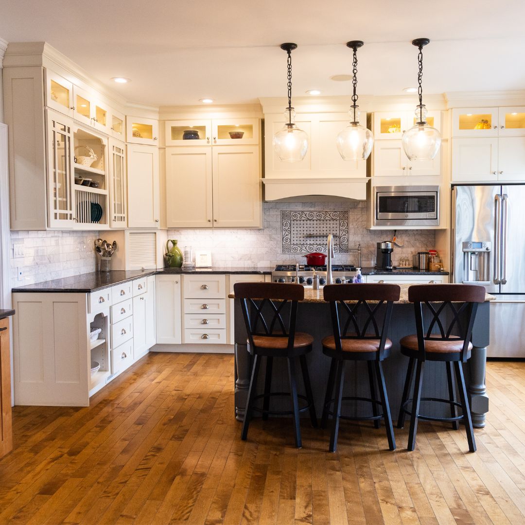 Elegant kitchen renovation featuring custom white cabinetry, granite countertops, and pendant lighting.