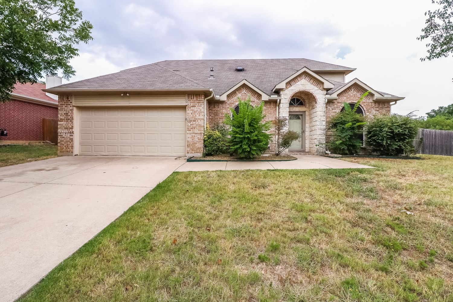 Front of home with arched, covered patio entrance and two-car garage at Invitation Homes Dallas.