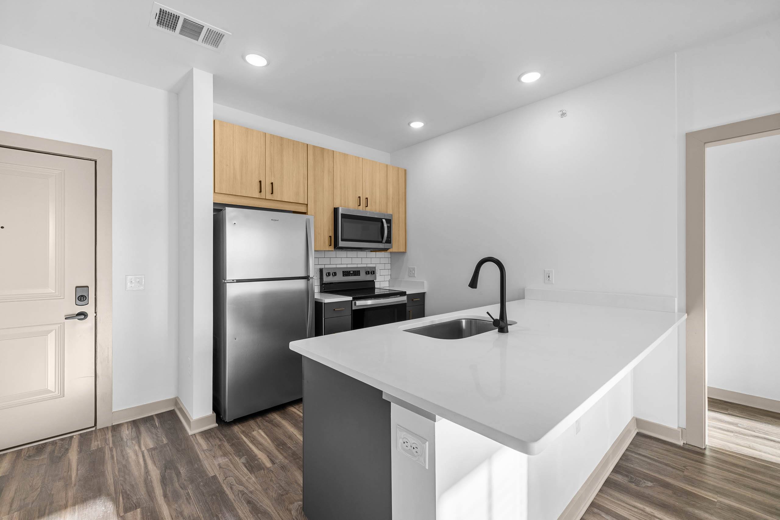 A kitchen with a white counter top and a black faucet