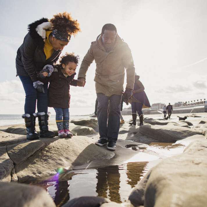 A family walking along a rocky shoreline.