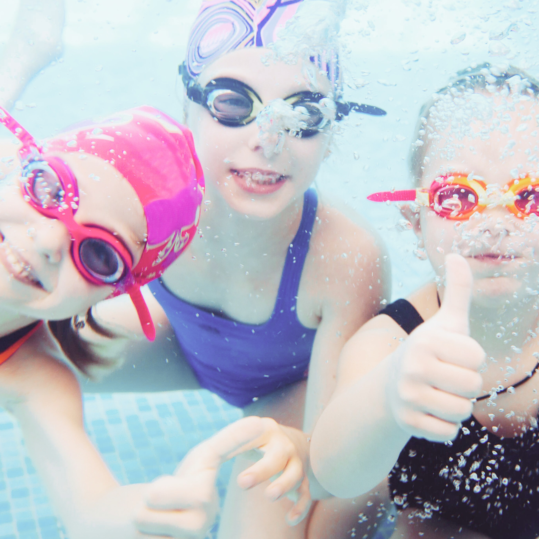 Happy kids swimming and having fun in a crystal-clear pool