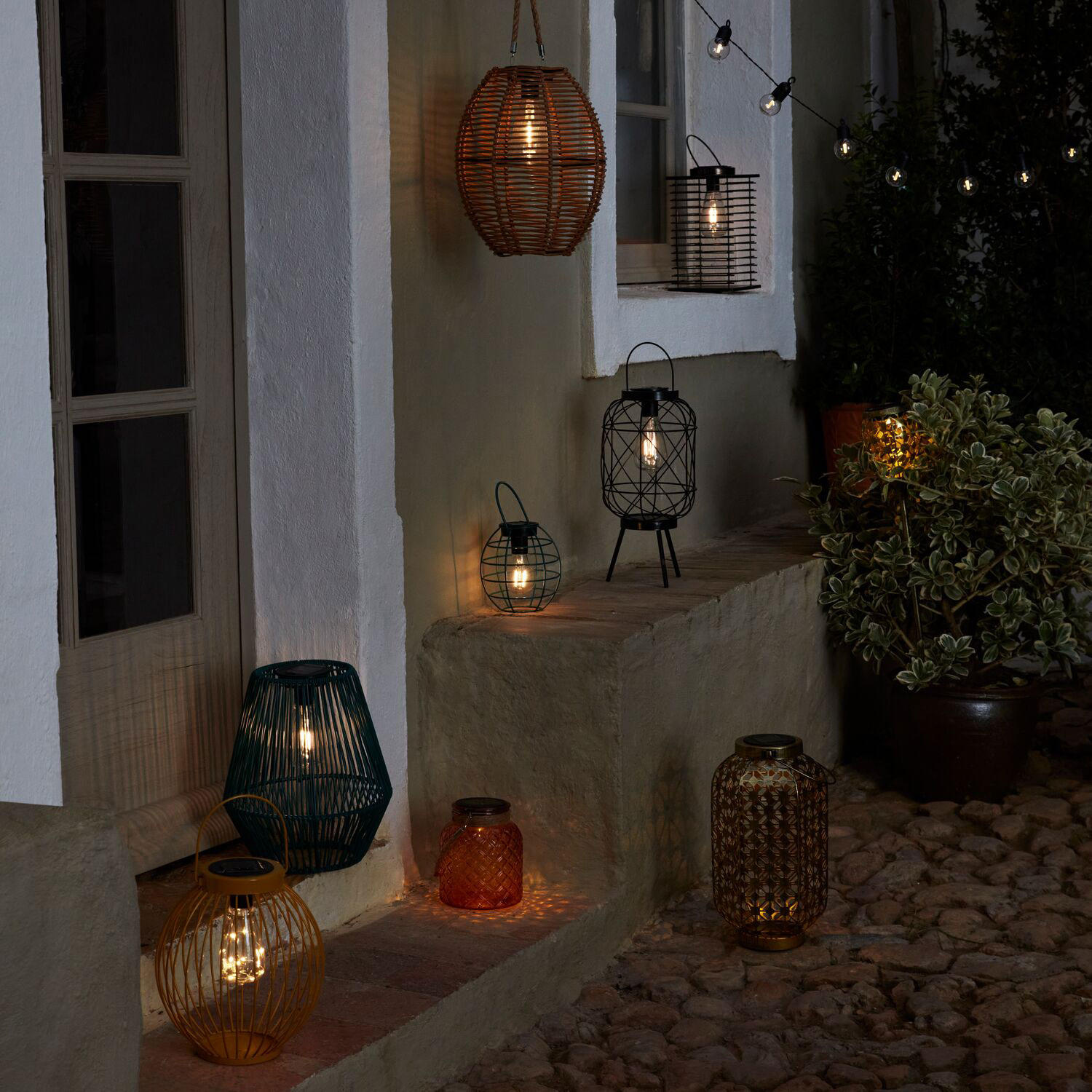 A selection of outdoor string lights and lanterns lit up at night