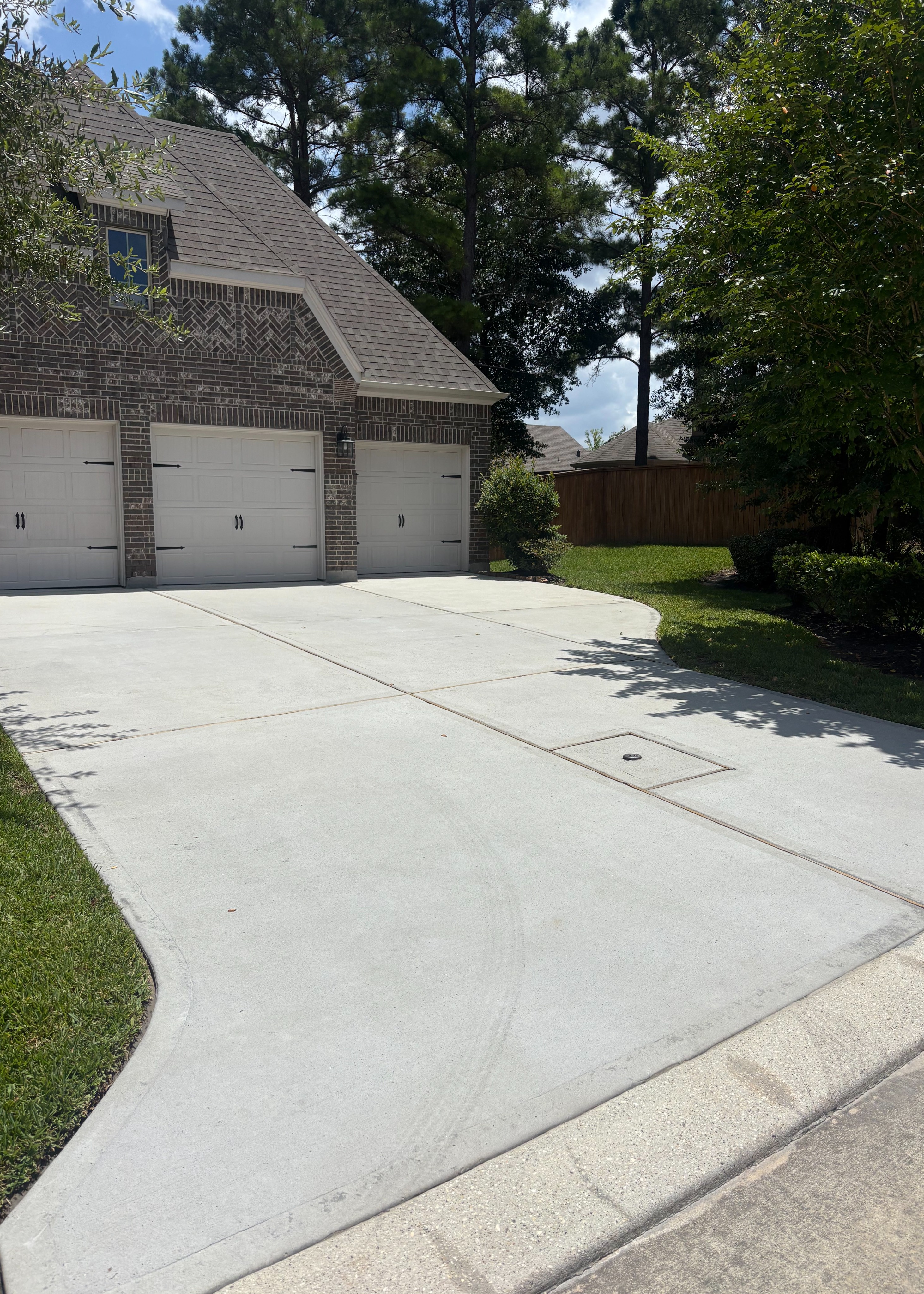 Freshly pressure-washed driveway with a clean, restored concrete surface, showcasing professional pressure washing services in Montgomery, TX by Integrative Soft Wash and Property Services.