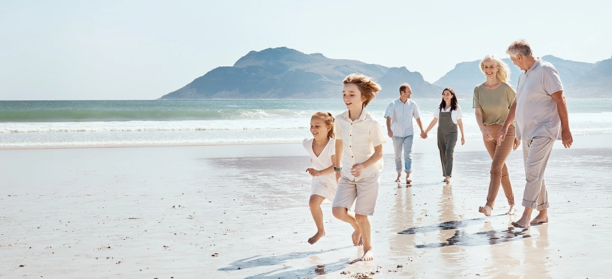 A multigenerational family walking along the beach together.