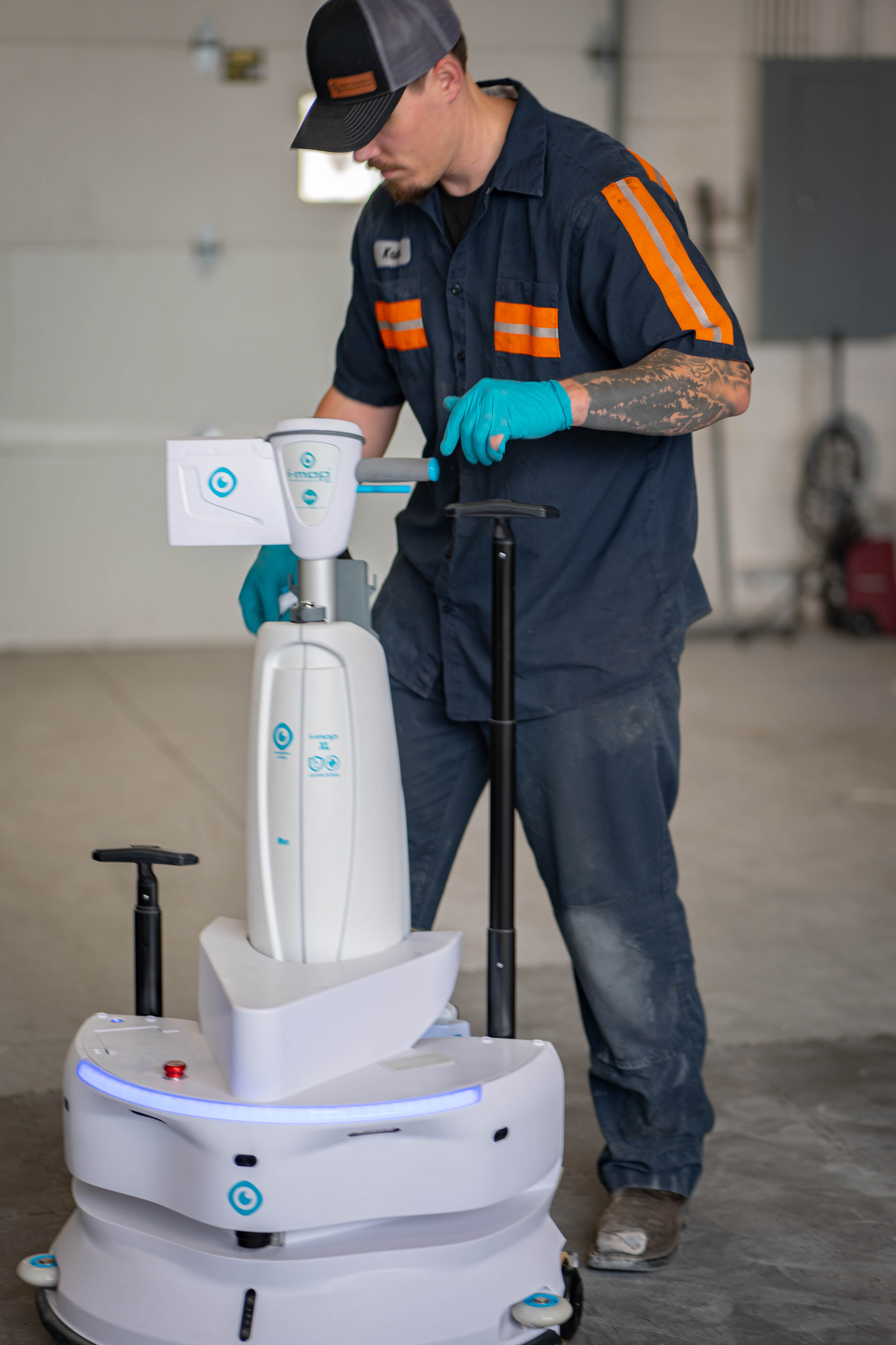 A technician adjusting and testing an advanced, next-generation autonomous robotic floor scrubber co-bot inside a commercial service facility.