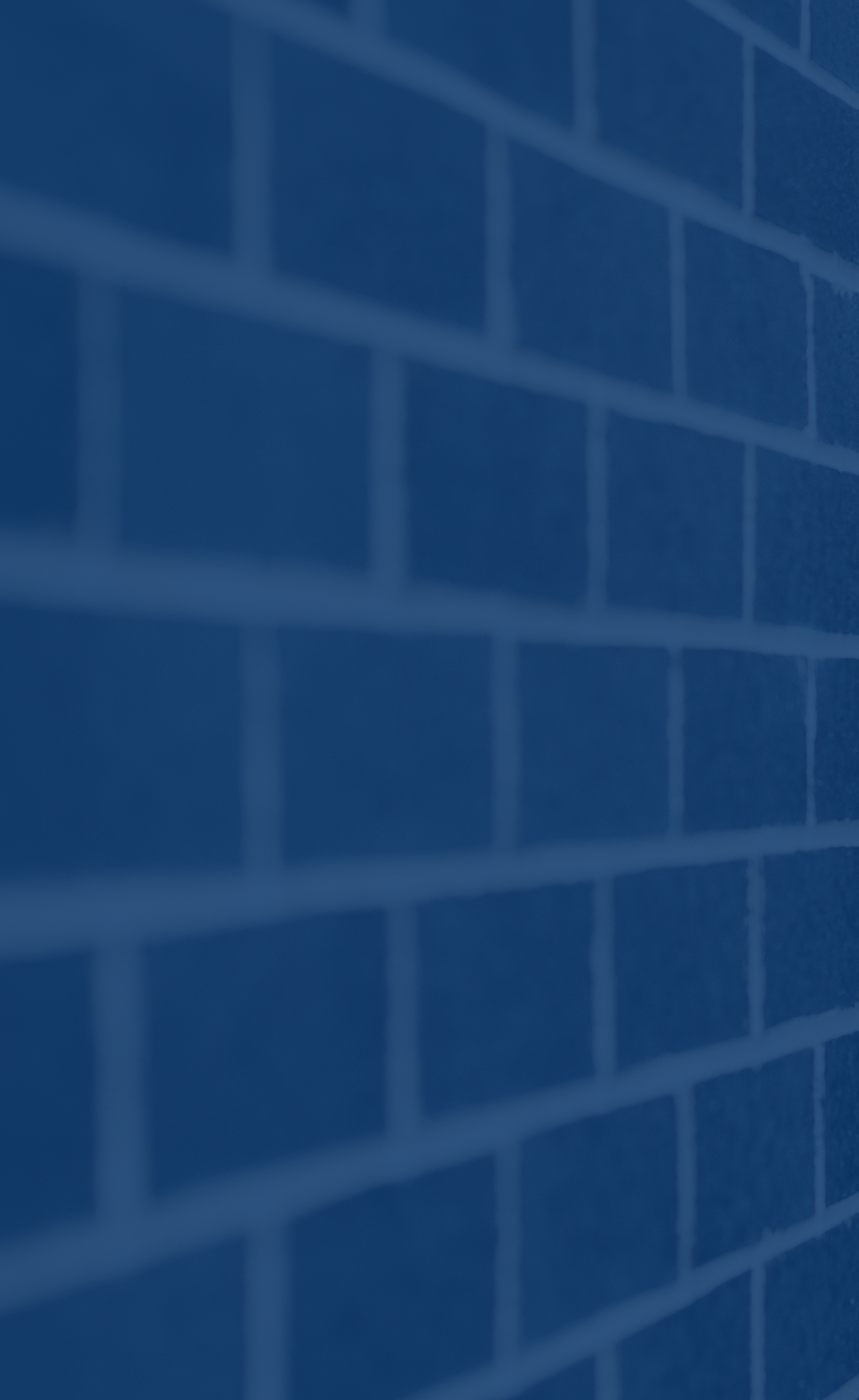 Ed Fairhurst casually leaning against a brick wall.