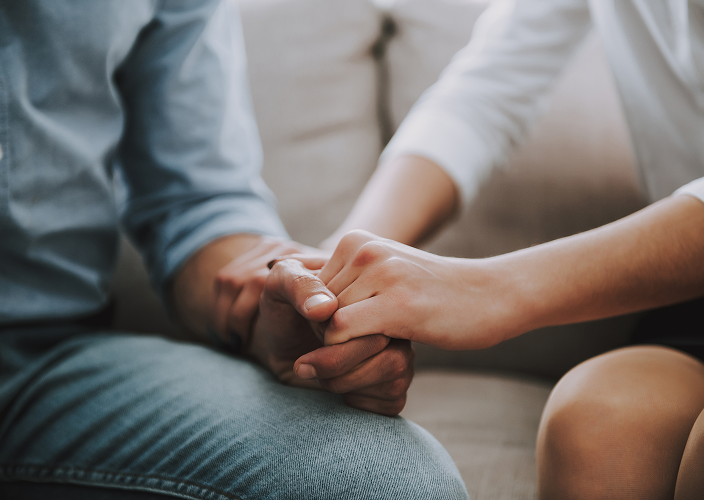 Close-up of two people holding hands.