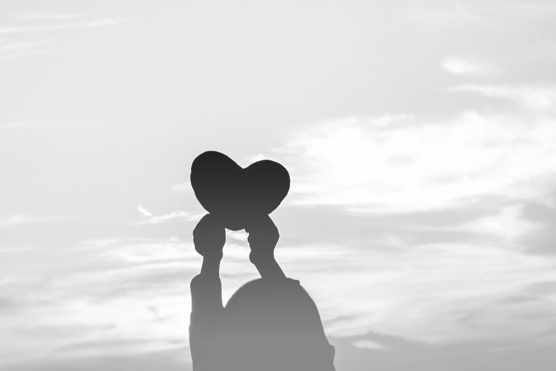 Silhouette of a child holding a paper heart.
