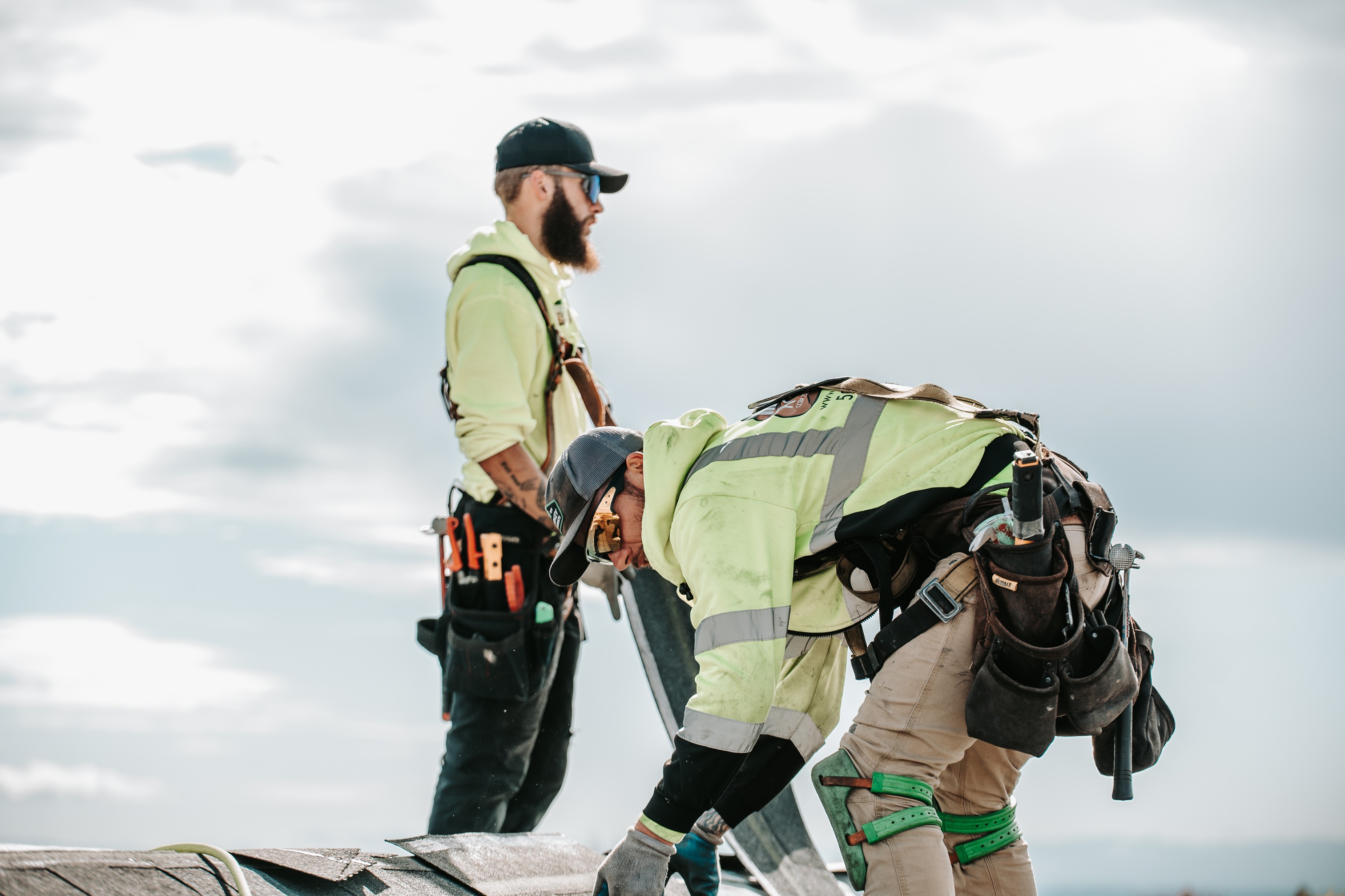 Two roofing professionals working together on a residential roof installation. 