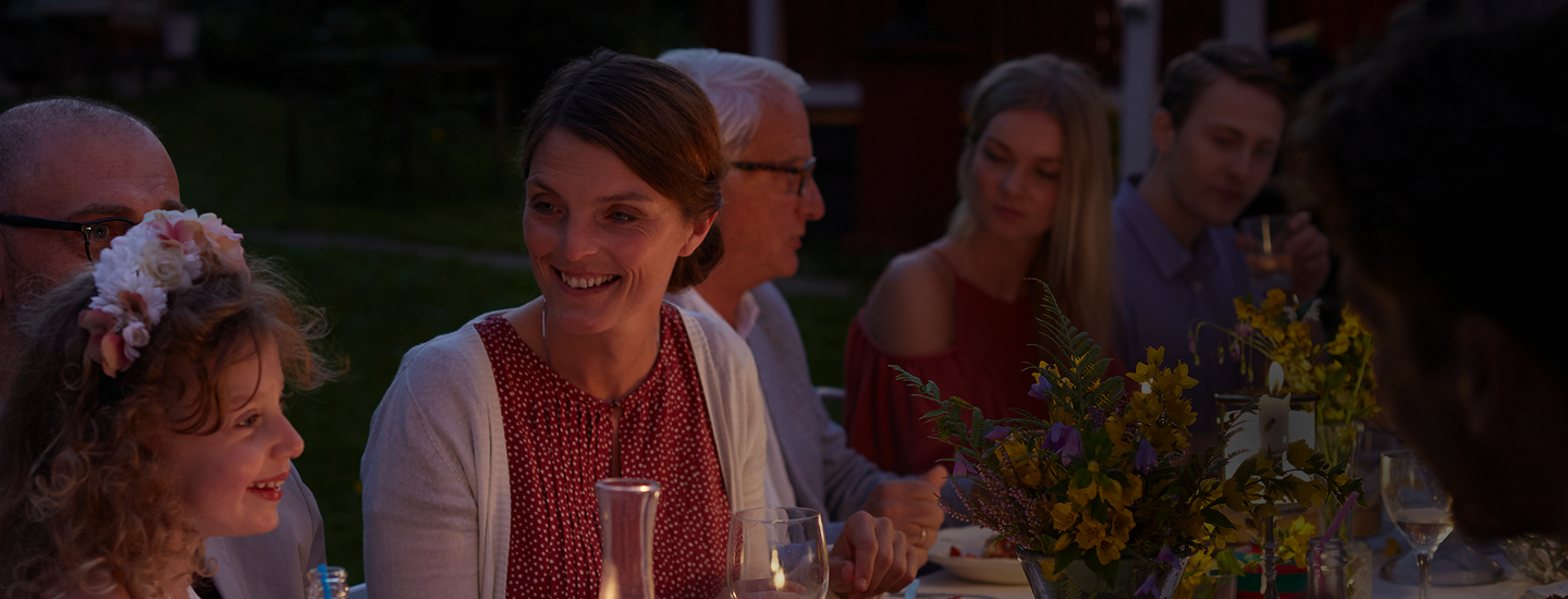 A woman looking lovingly at a child during a multigenerational family dinner outside.