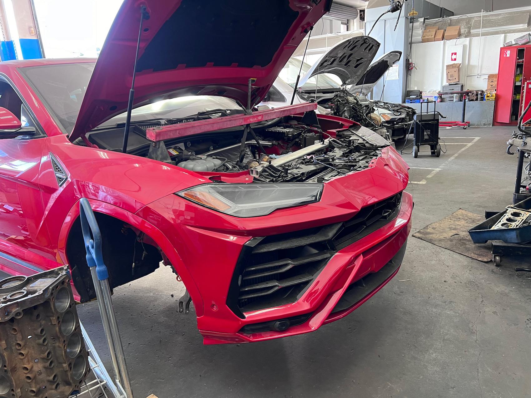 Detailed photo of Lamborghini Urus waiting at auto body shop parking lot for collision repair