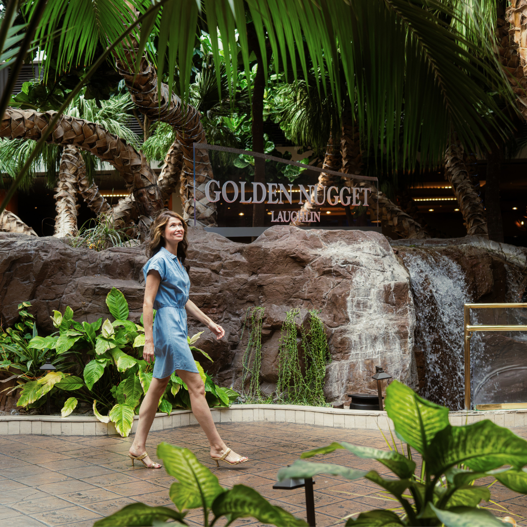 Guest walking through a lush indoor atrium with palm trees and a waterfall
