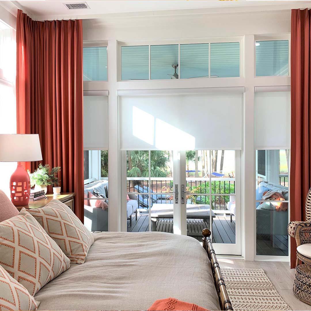 You'll create the ultimate combination of design and functionality by layering your window treatments. Here, these motorized roller shades provide light control, while these rust-colored drapes match the red details throughout this bedroom design.
