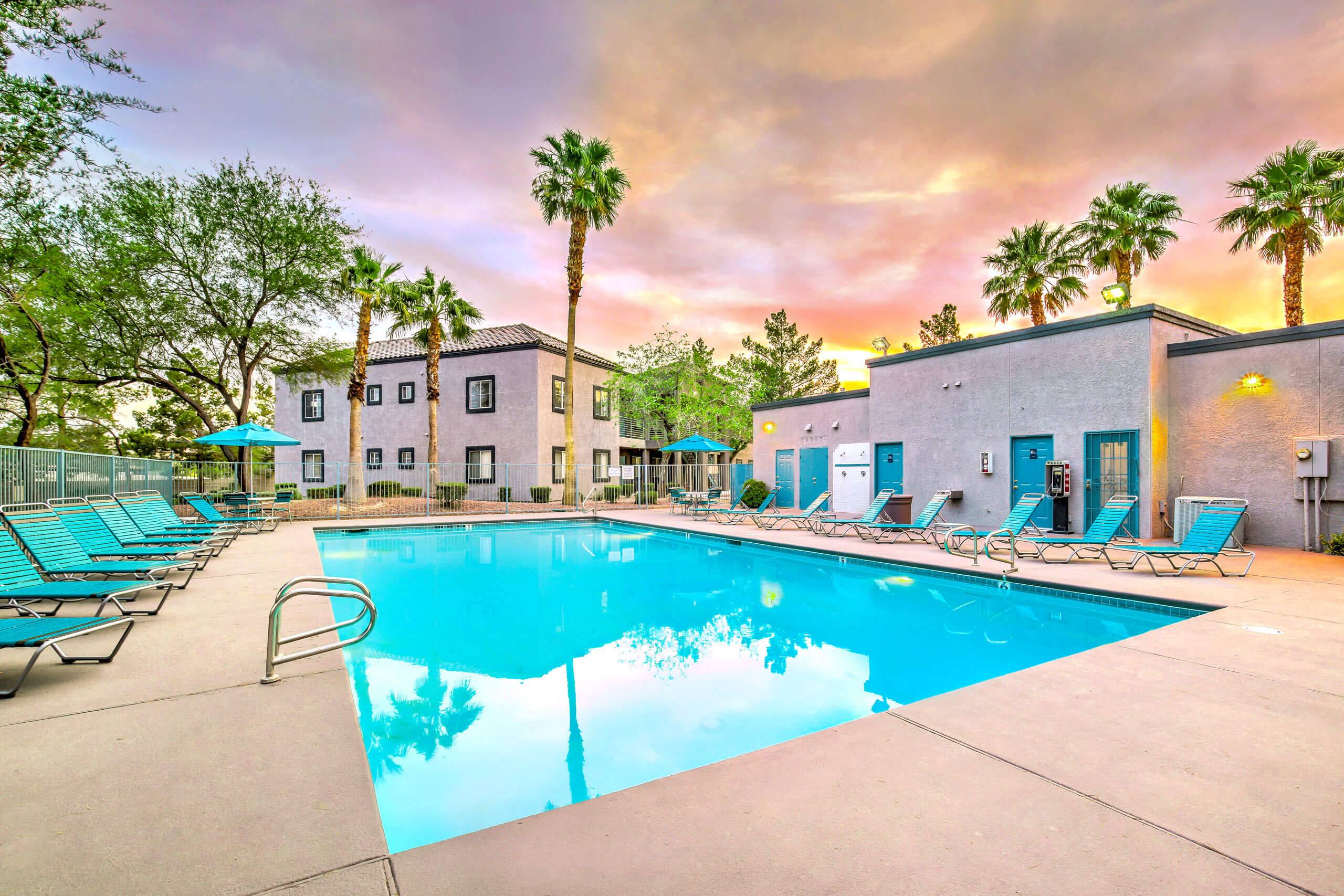 A swimming pool surrounded by lounge chairs and palm trees
