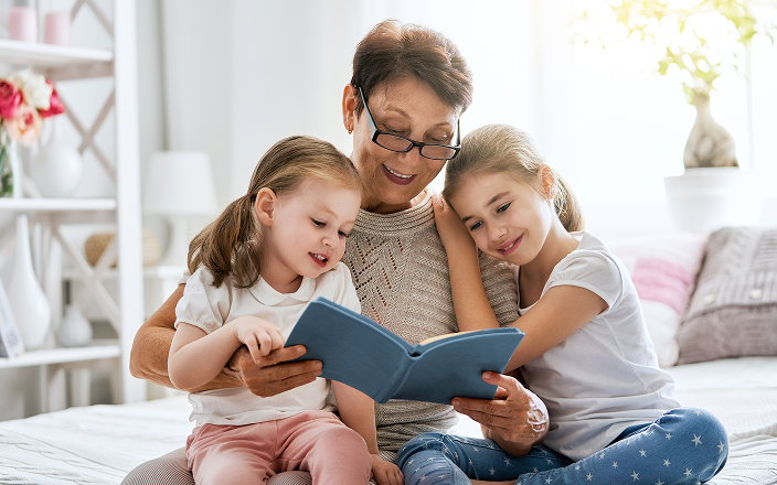 Grandmother reading to her two young granddaughters.