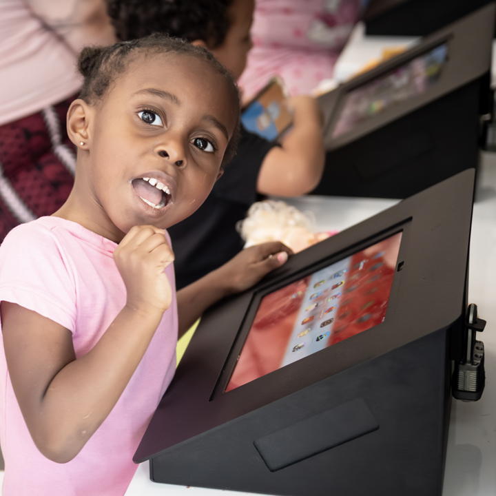 Young child enjoying a touchscreen tablet in the family-friendly kids' area at Speed Queen Laundry. 