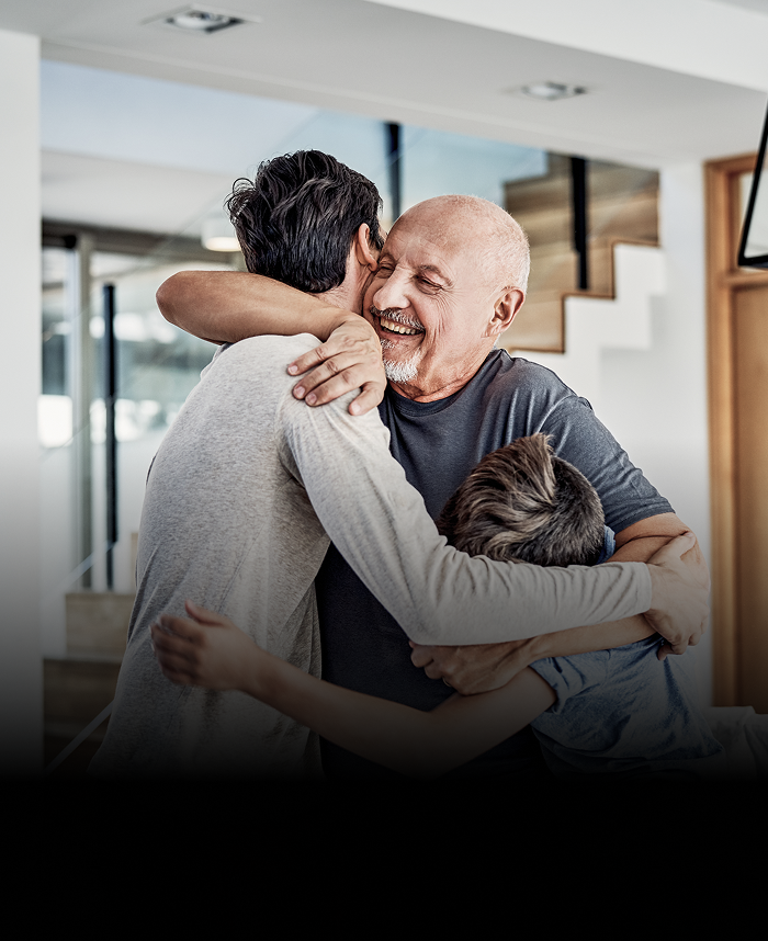 A grandfather hugging his son and grandson.