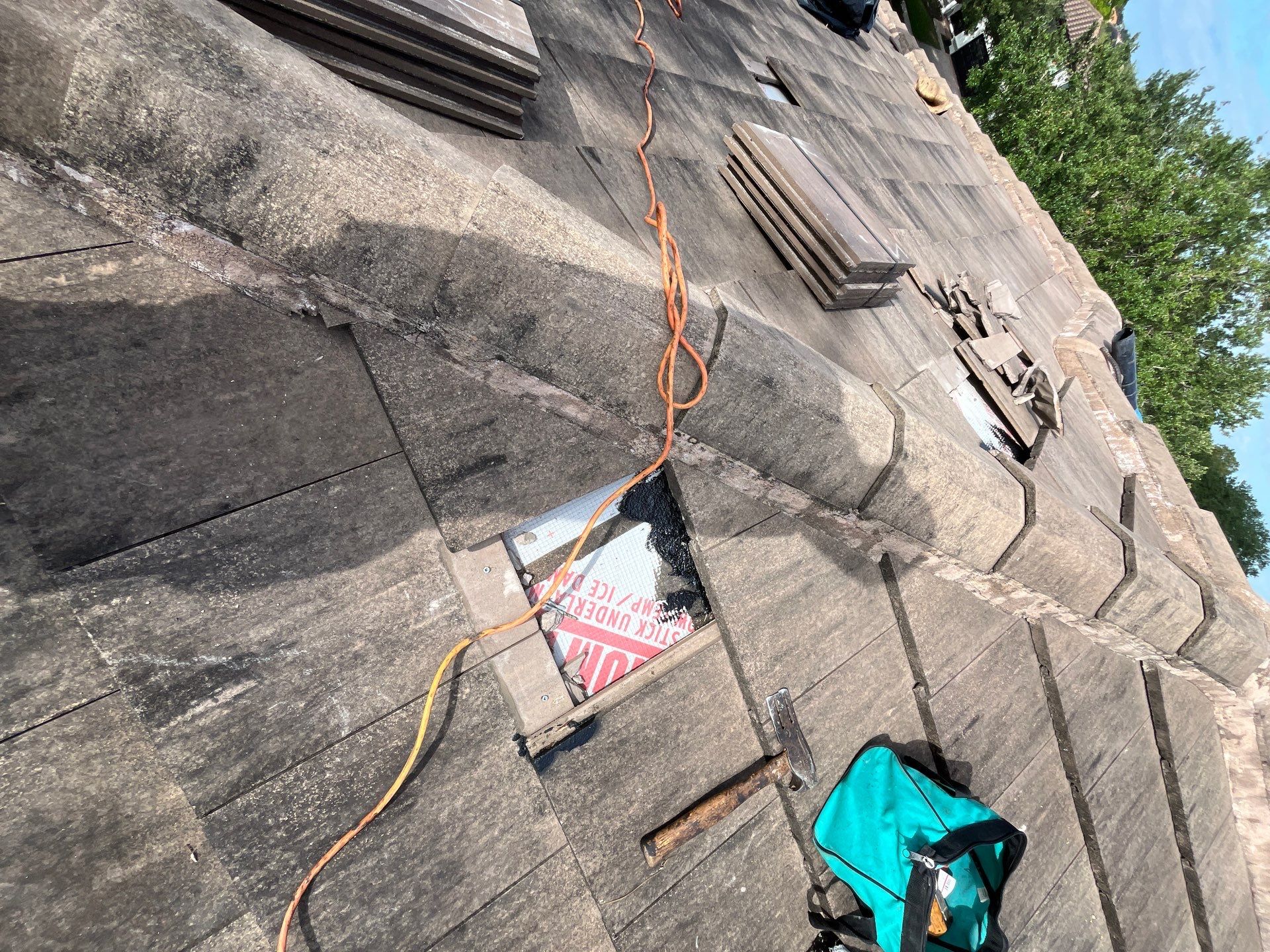 View of a roofing project with exposed underlayment and tools on the roof, highlighting preparation  