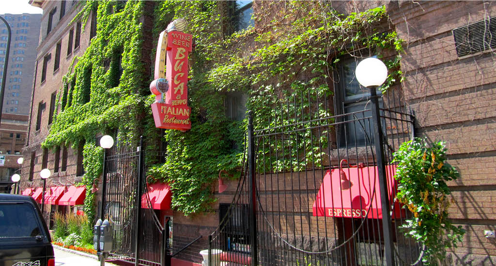 Buca di Beppo Minneapolis street view showing a brick building with greenery decor and a vertical Buca street sign.