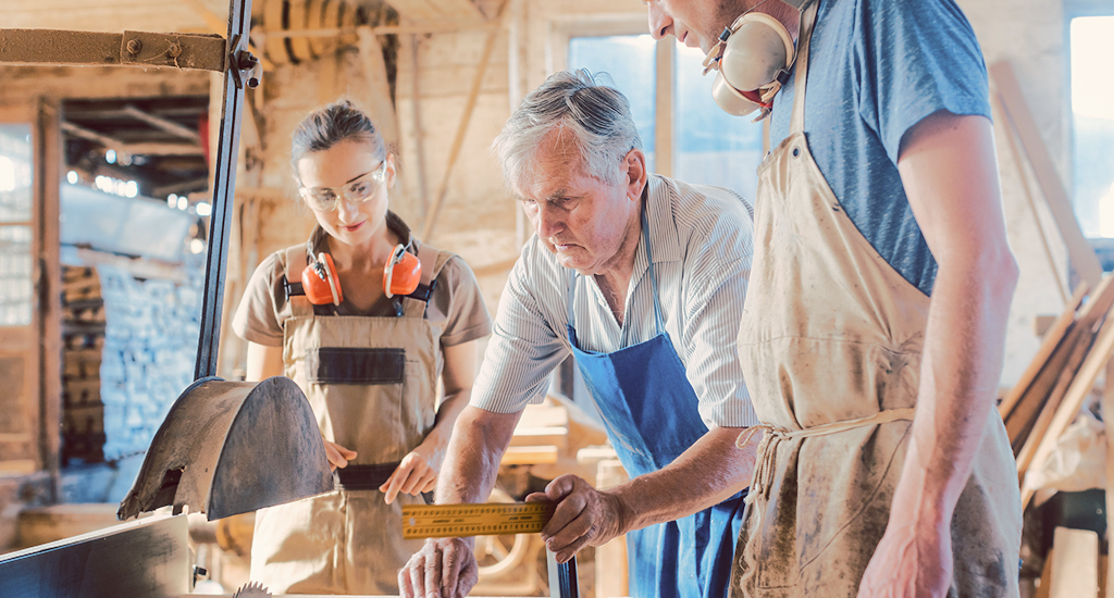 Three people working in a woodshop.