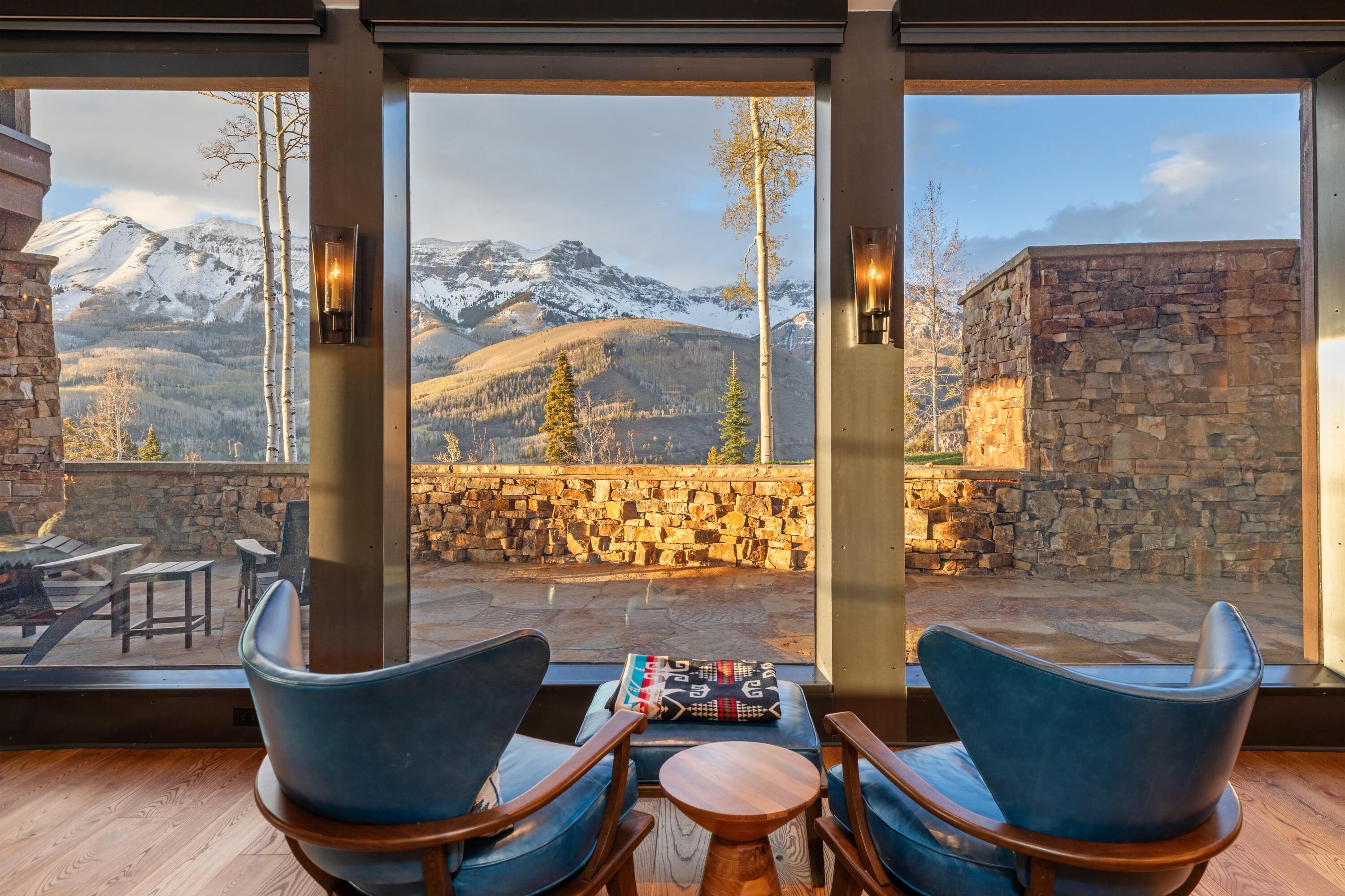 Mountain-view living area with blue lounge chairs and a stone terrace.