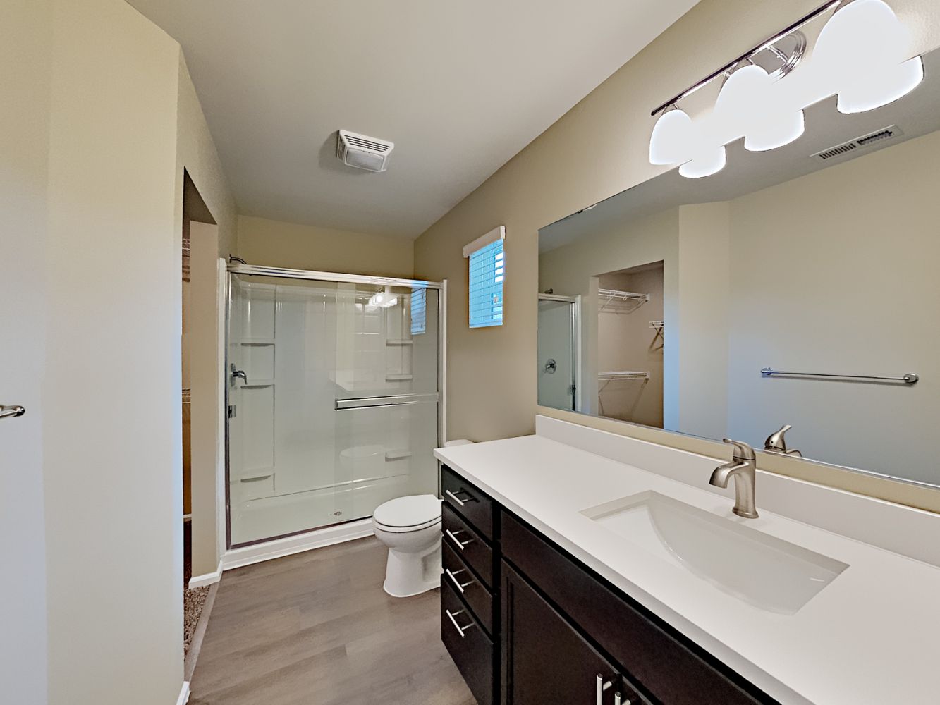 Bathroom with luxury vinyl plank flooring, modern light fixtures and a spacious shower at Invitation Homes Seattle.