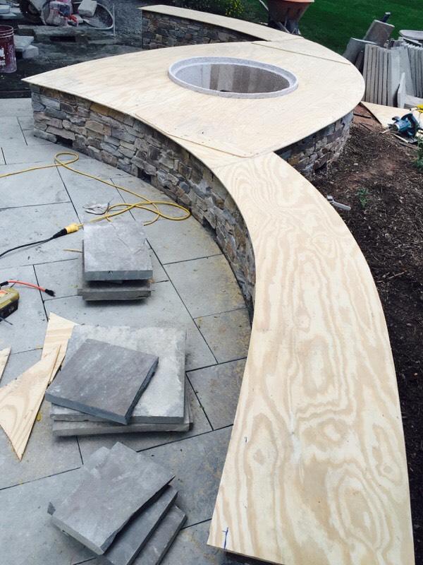 Stone fire table under construction by Garden Artisans: During our first meeting our client expressed his love for the outdoors and was adamant that we use fine natural stone materials to build his project. His home overlooks the 15th hole of a golf course and the Sourland mountain range. This large natural stone fire table with seating invites family and guests to gather and enjoy cocktails, surrounding perennial plantings, golf course views, and beautiful sunsets over the Sourland mountain range! We received a text message and a picture from our client on a Friday evening while he was enjoying some red wine and his new fire feature: 