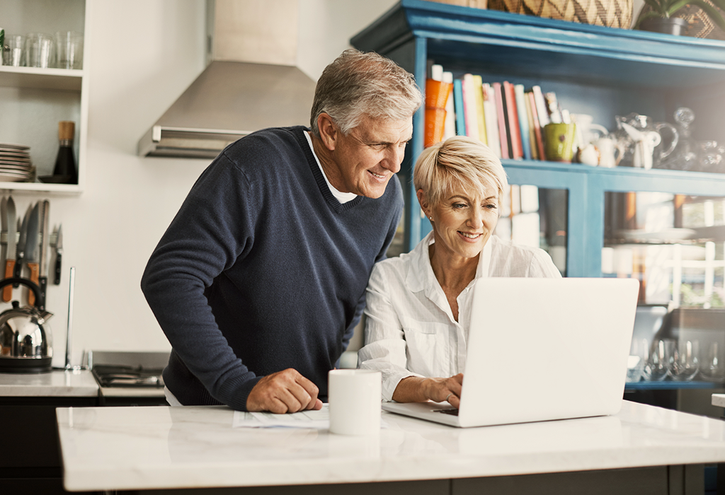 A husband and wife reviewing their financial statements from home on their laptop.