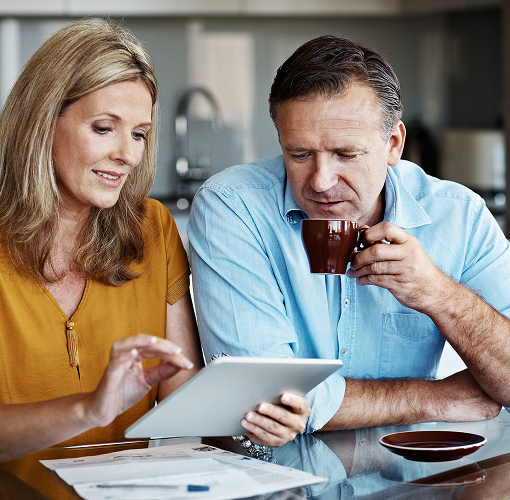 A couple in their kitchen reviewing their financial statements.