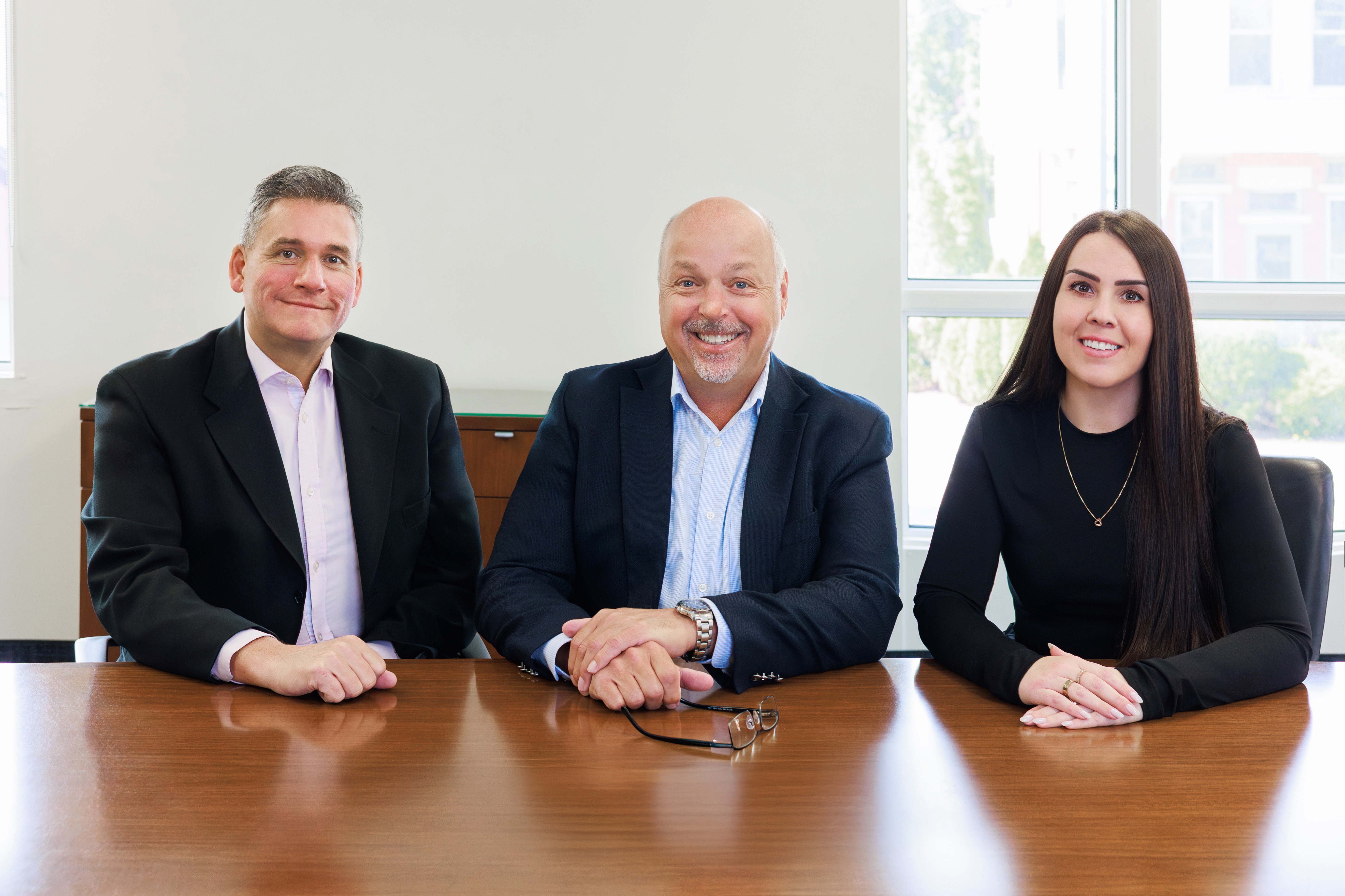 Team photo of Robert Corchis, Jeff Utley, and Ashleigh Deacon, sitting at a meeting table.