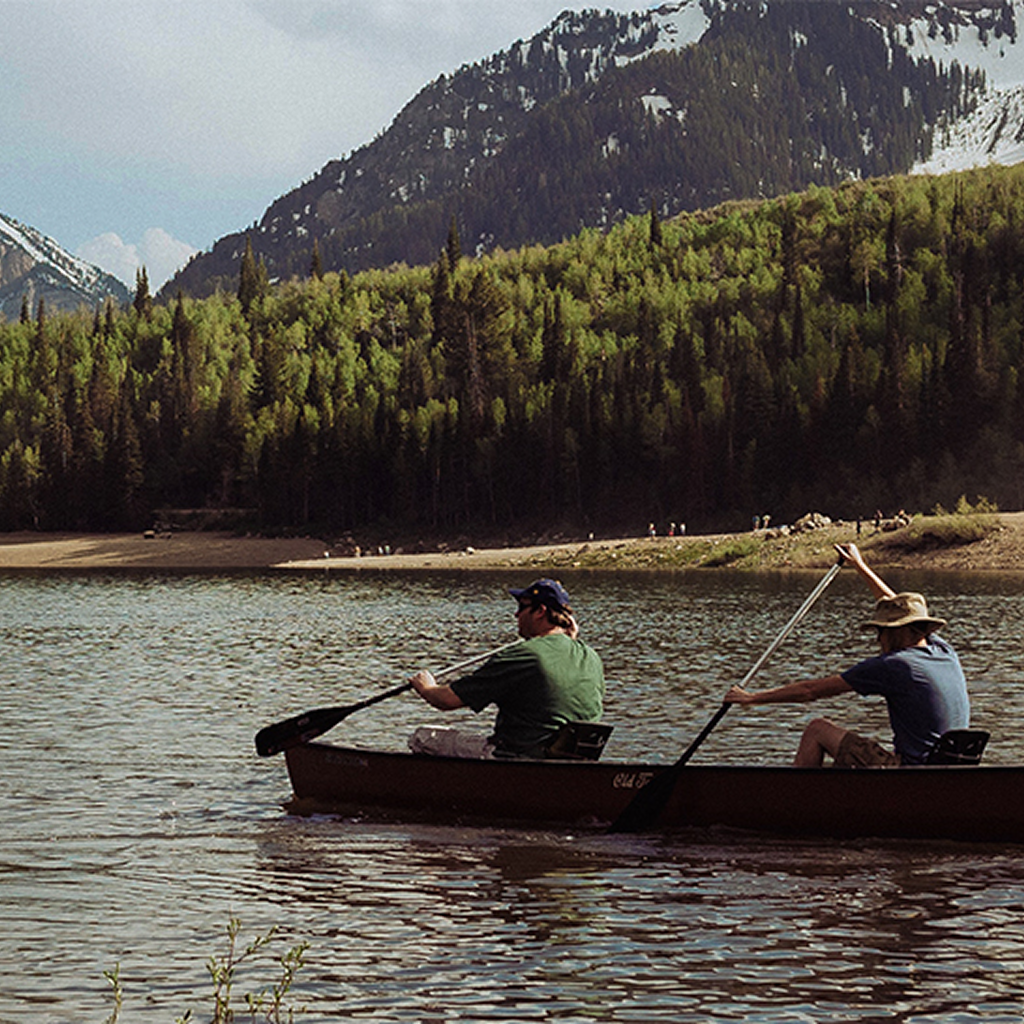 People canoeing with mountains in the background.