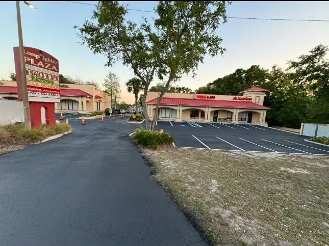 Newly paved commercial property entrance featuring clean asphalt, sharp lane markings, and organized traffic flow improvements for business accessibility and safety.