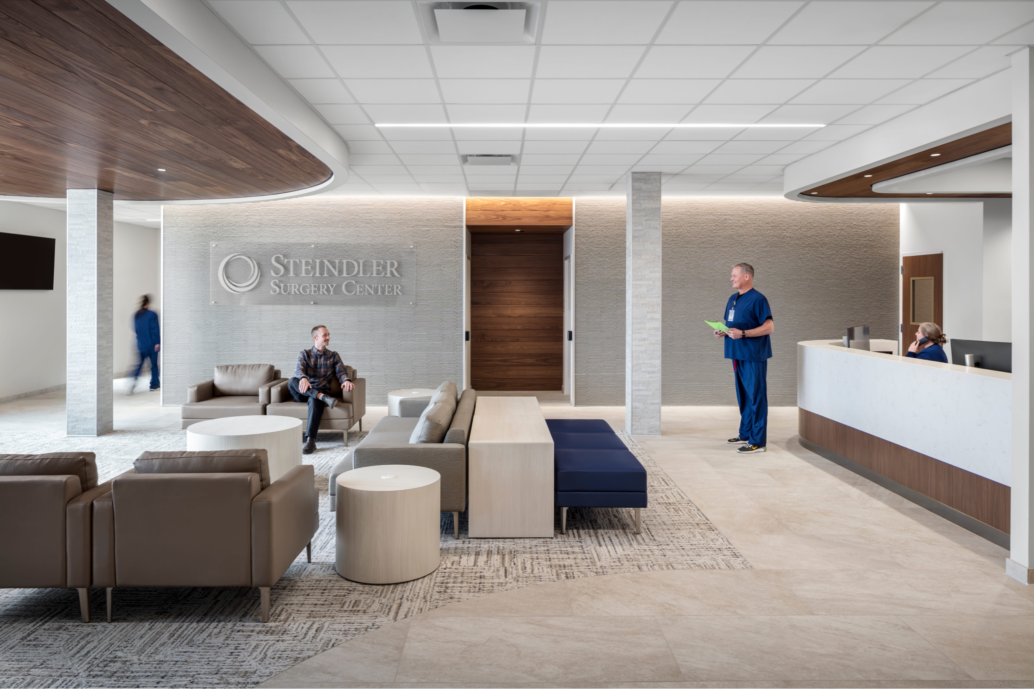 Interior view of a bright, modern waiting and reception area at Steindler Surgery Center, featuring contemporary seating, natural wood accents, and a staffed front desk in a clean clinical environment.