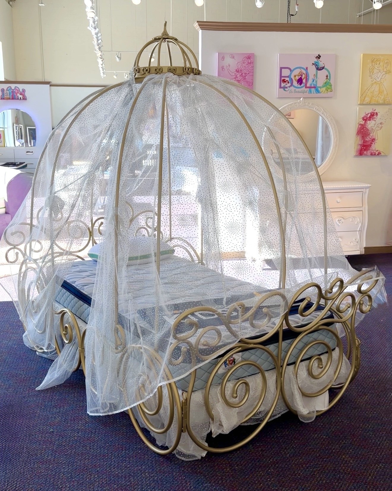 See this gold carriage-style canopy bed with sheer canopy at Rooms To Go Kids, perfect for a Disney princess room in 2026.