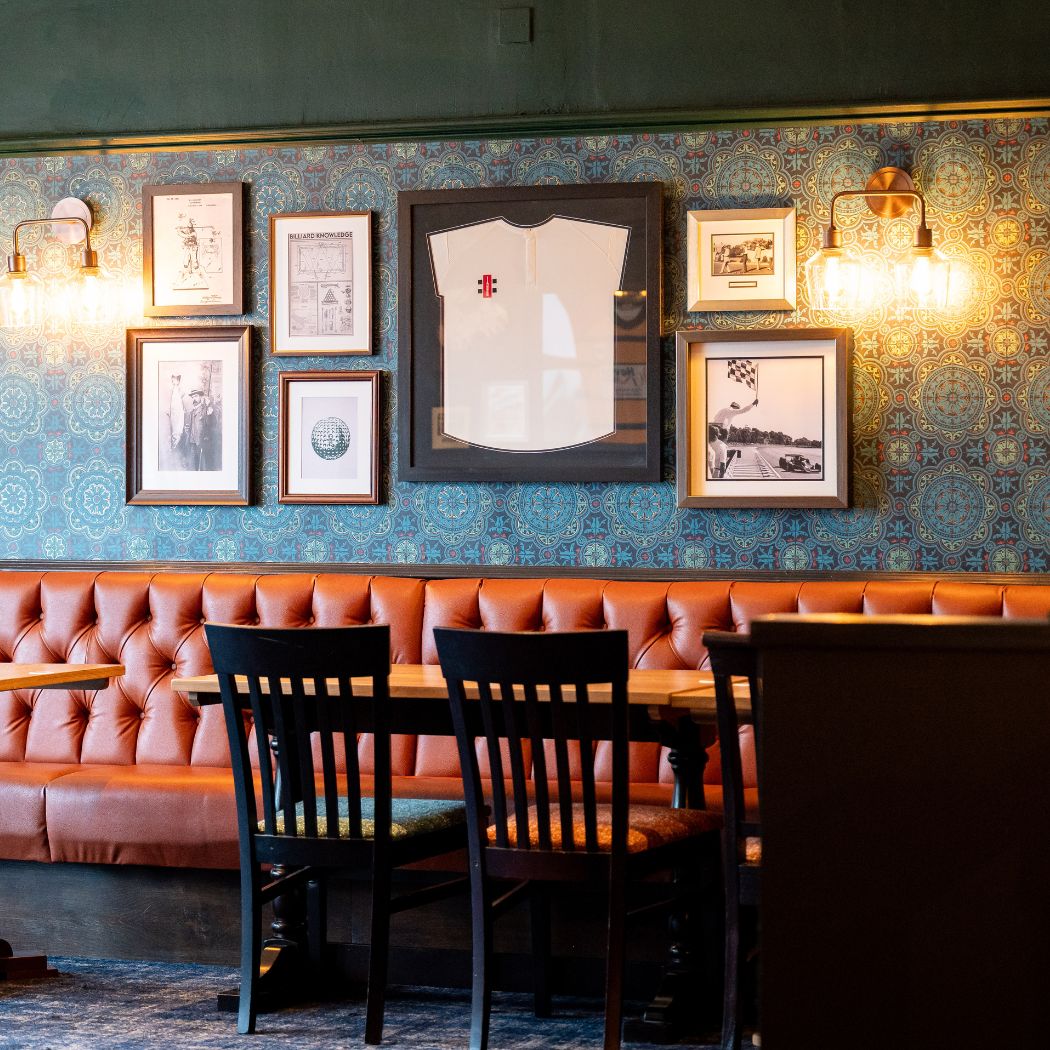 Comfortable booth seating with patterned walls and framed artwork, creating a warm and inviting dining space.