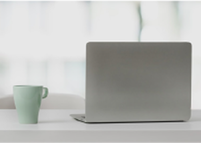 A laptop next to a mug of coffee.