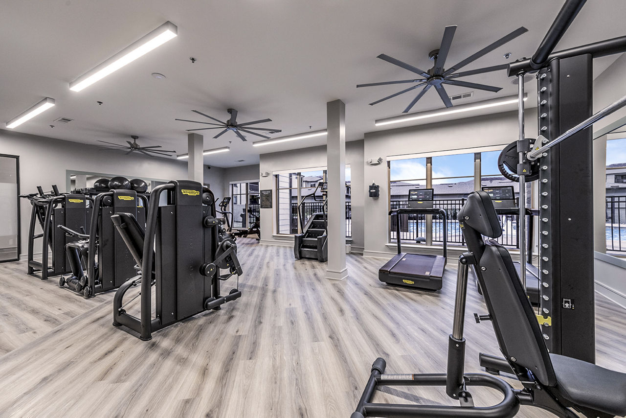 A spacious gym with treadmills, weights, and a ceiling fan. 