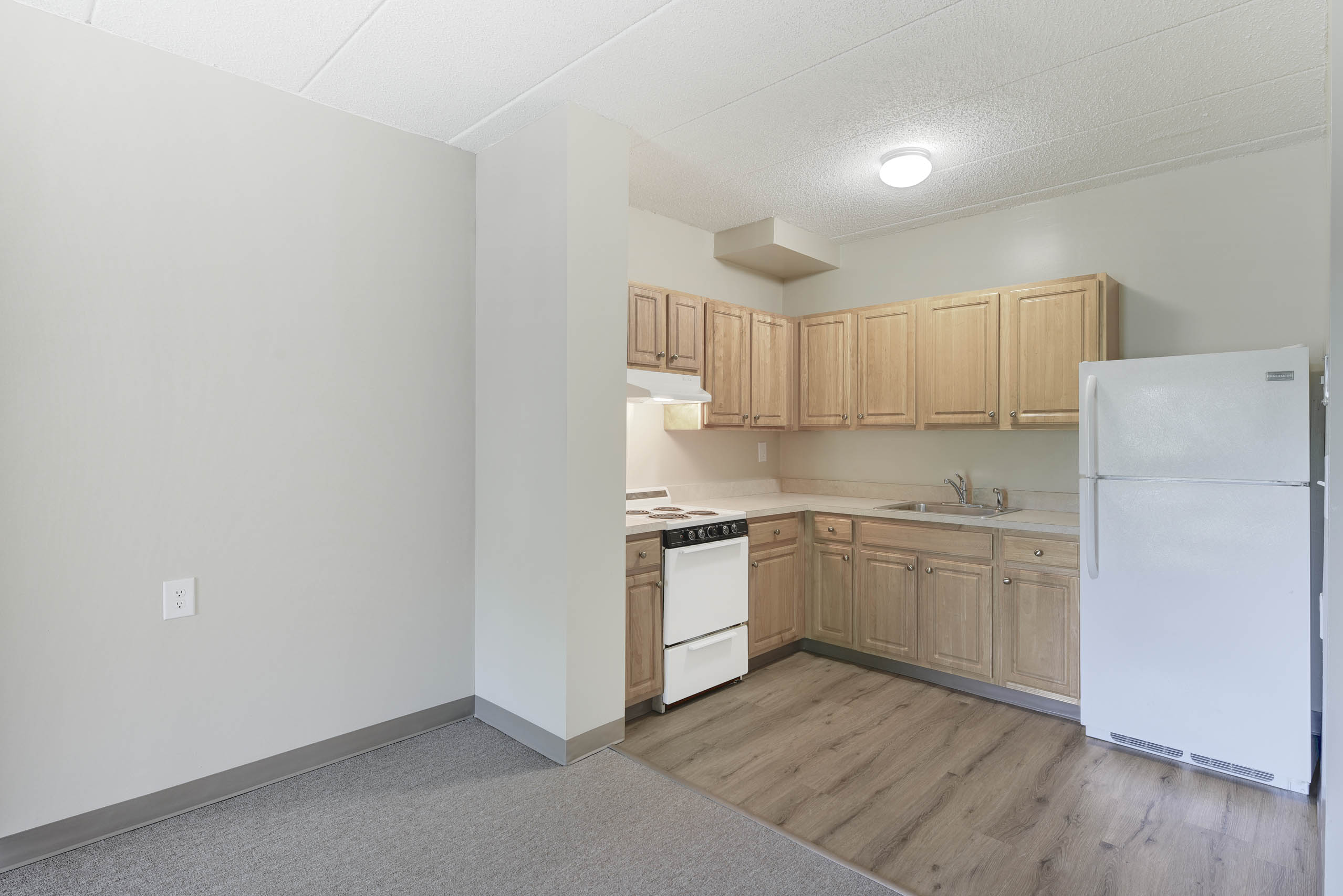 A kitchen with wooden cabinets and a white refrigerator.