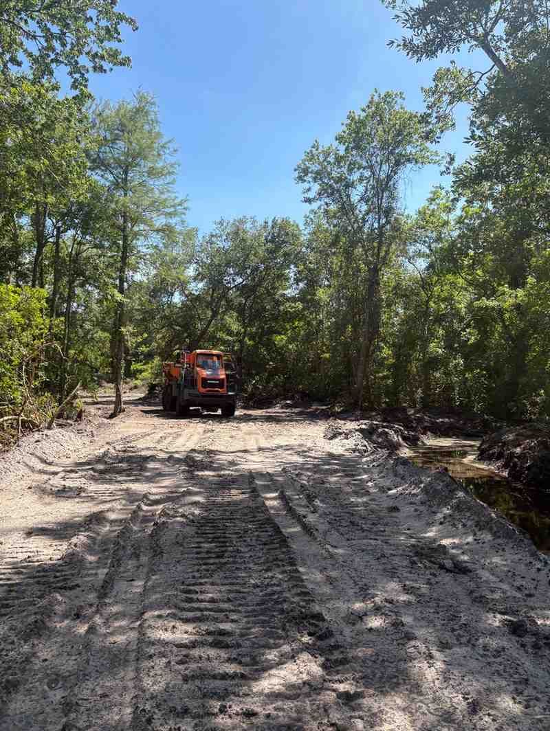 Heavy equipment operating along a developing access road, improving transportation routes through challenging terrain while supporting drainage management and long-term property accessibility requirements.